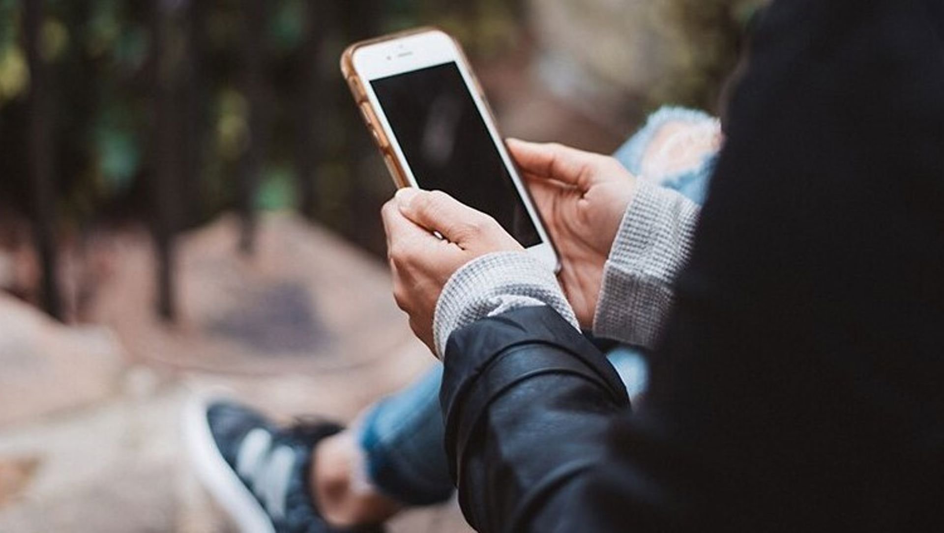 Person using a mobile phone whilst sitting in a park