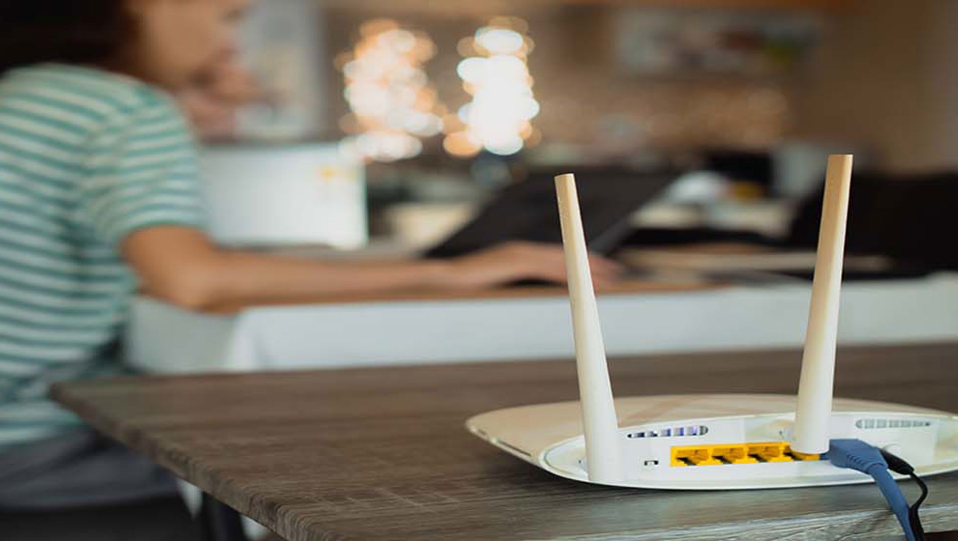 Person using laptop with broadband router on table 