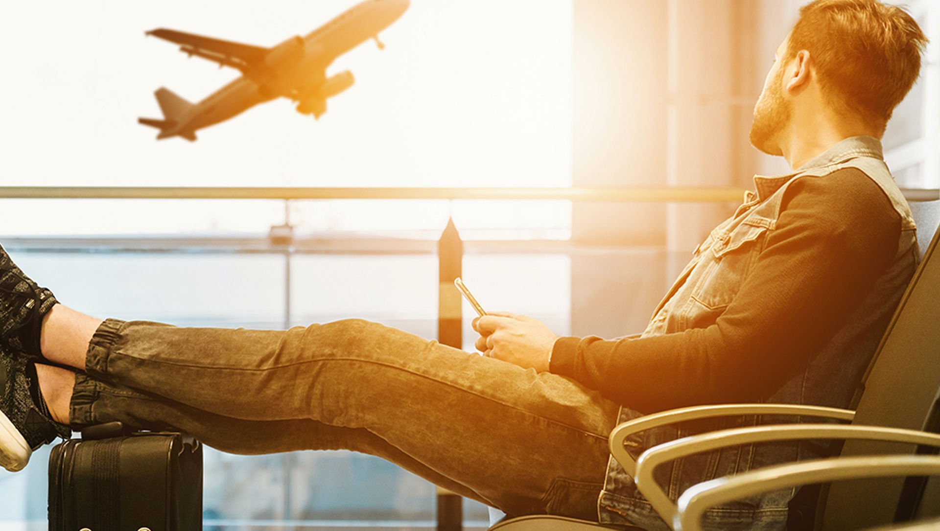 A man watching a plane taking off from inside an airport