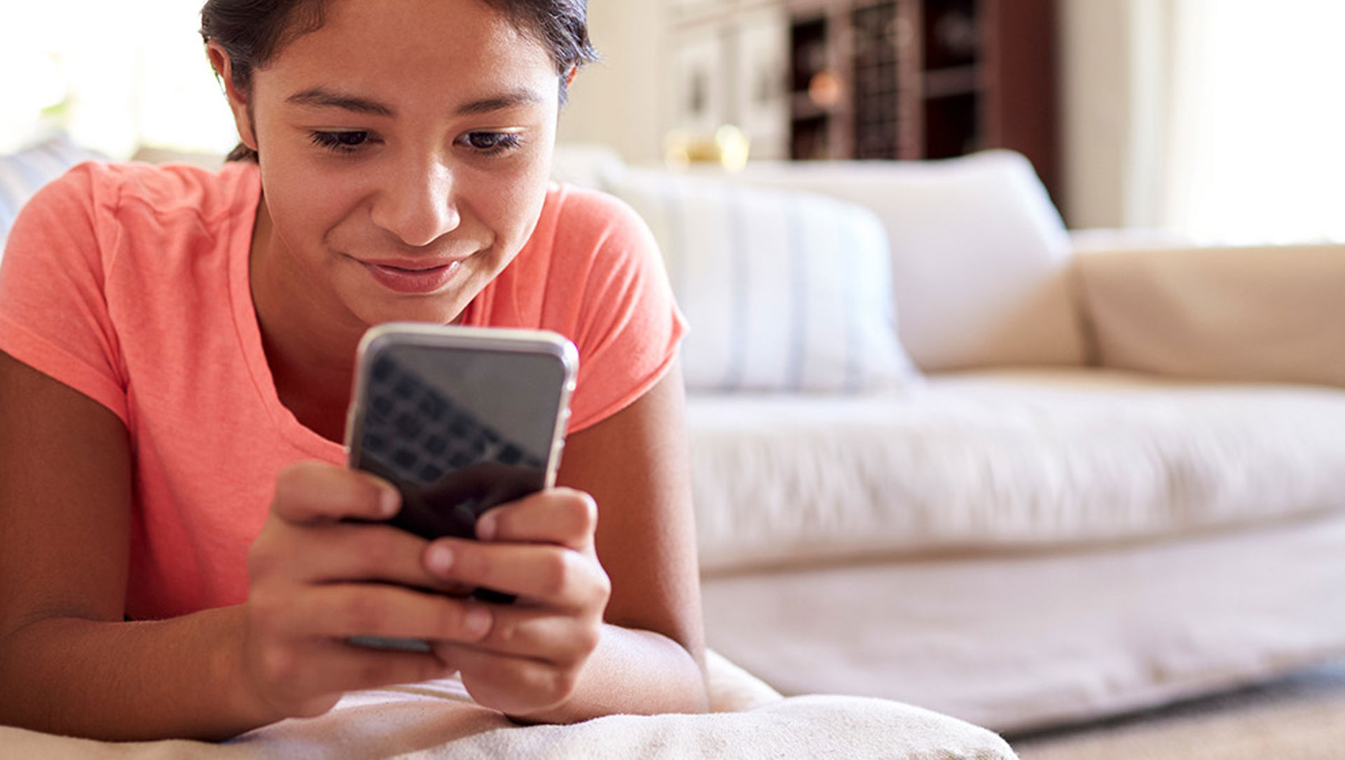 Teenage girl using smartphone on sofa