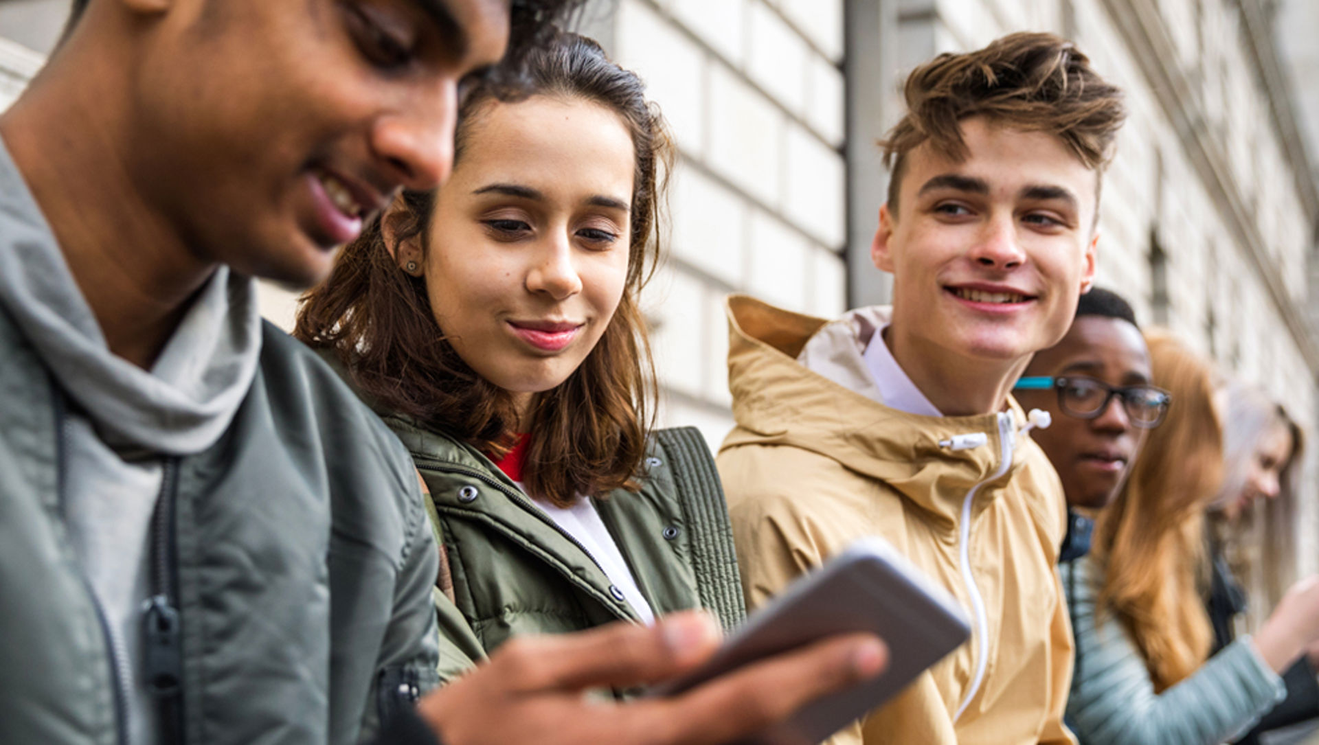 Teenage students using smartphones on a school break