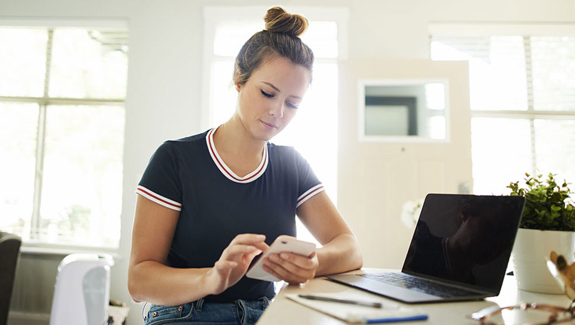 Young woman using a mobile phone while working at home