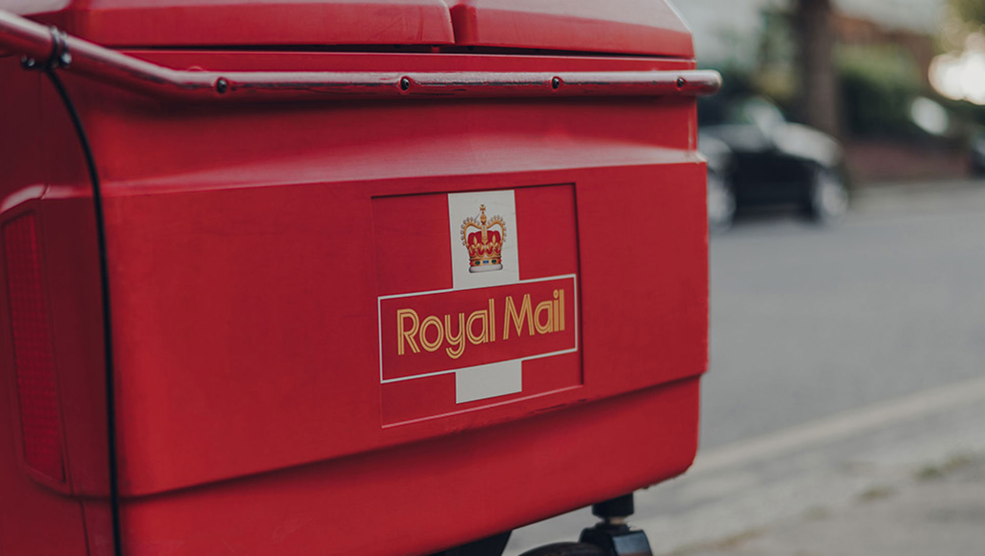 Red delivery troll belonging to Royal Mail on a street