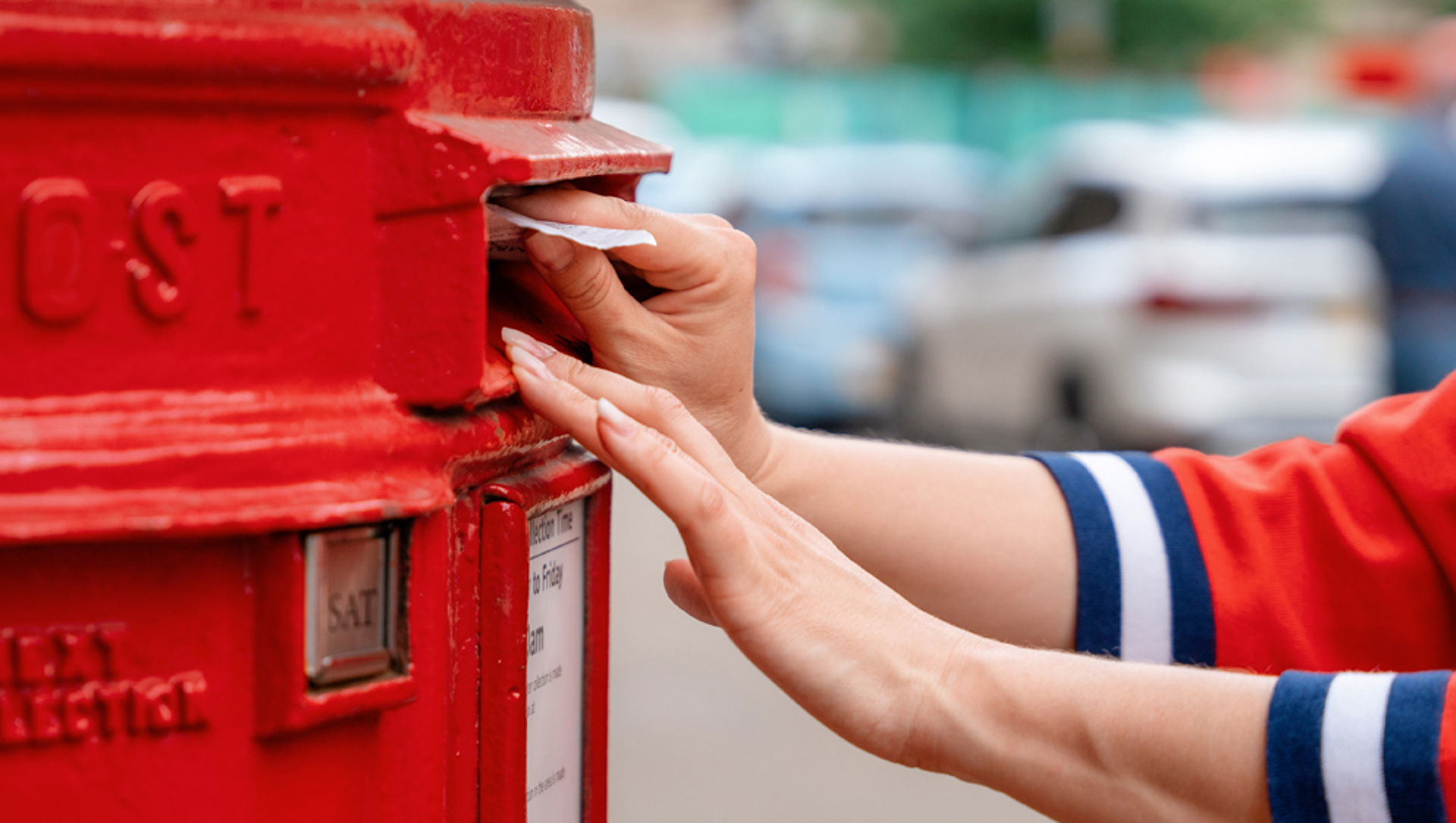 Woman in red jumper posting a letter