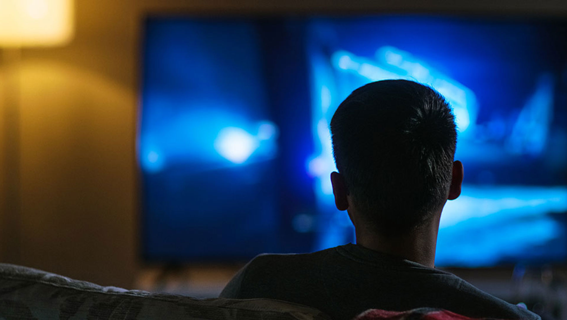 A man sitting on a sofa watching television