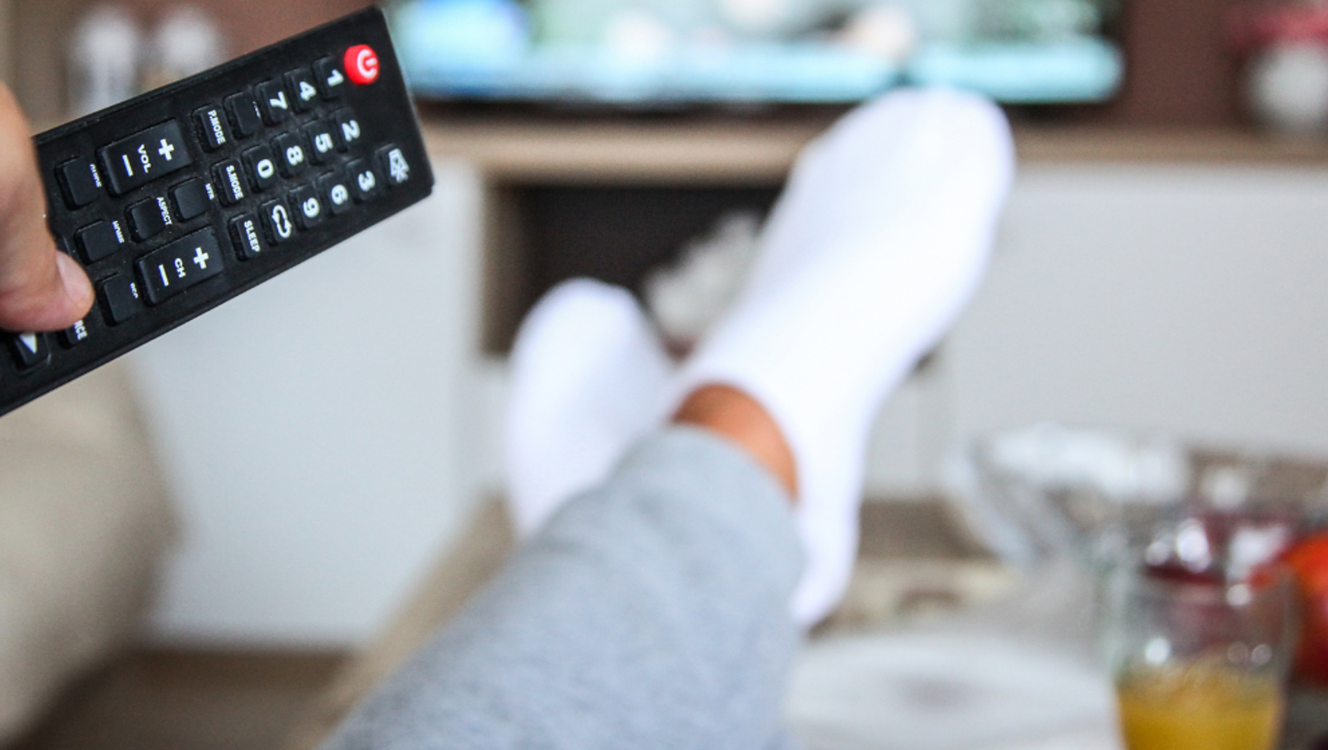 A person pointing a remote control at a television screen