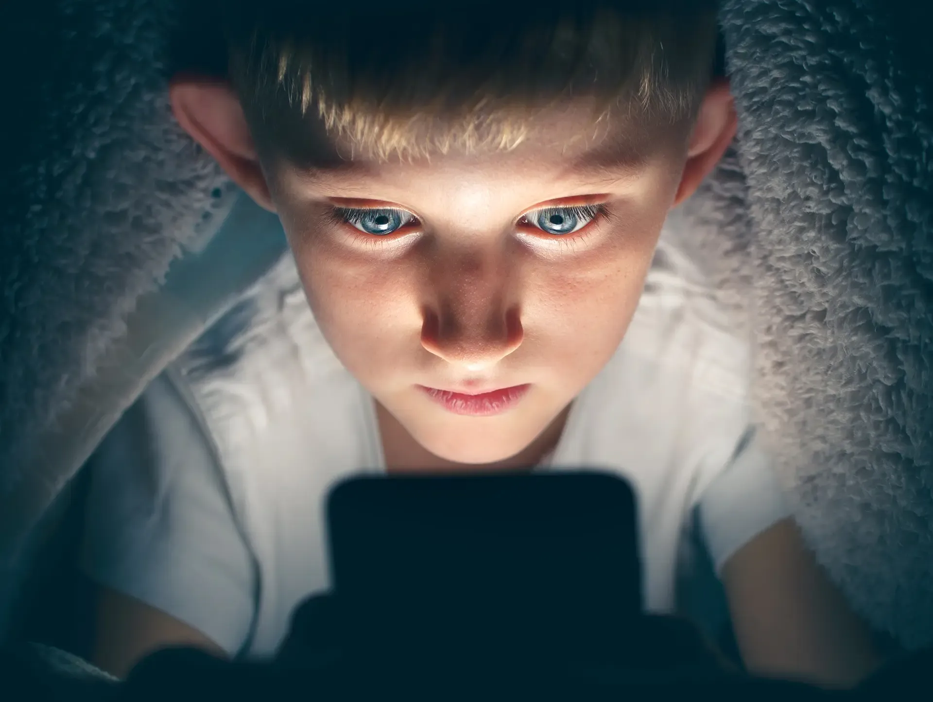 Young boy looking at a smartphone at night