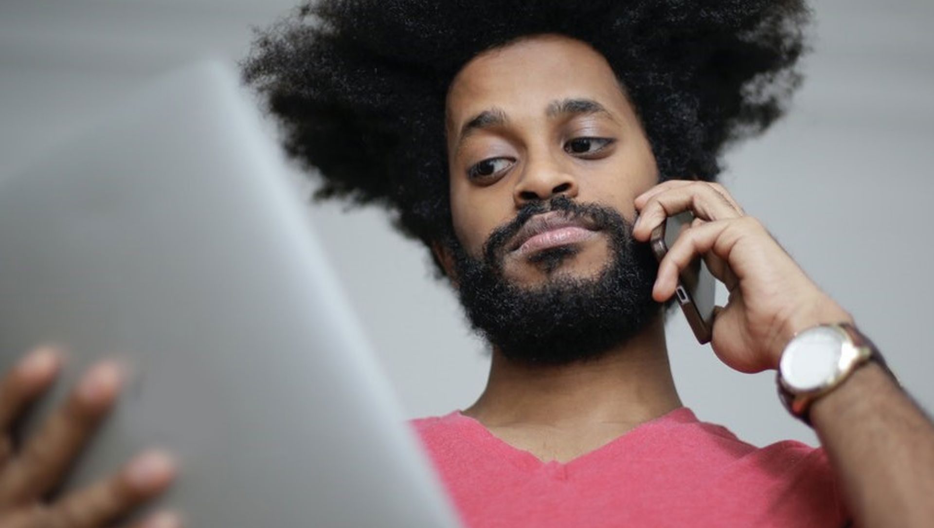 Man uses a tablet while speaking on a mobile phone